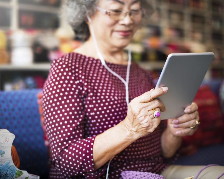 Warm portrait of a person wearing reading glasses with a tablet